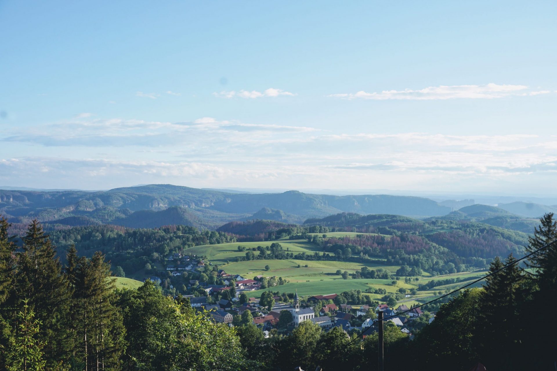 Ausblick auf Saupsdorf bei Sebnitz - Concredis Stuerberatung in Sebnitz Ausblick auf Wälder, Wiesen und Felder. Im Vordergrund sieht man den kleinen Ort Saupsdorf. Im Hintergrund kann man schon das Elbsandsteingebirge erkennen. Nicht weit davon liegt Sebnitz, wo auch die Concredis Steuerberatung ist.
